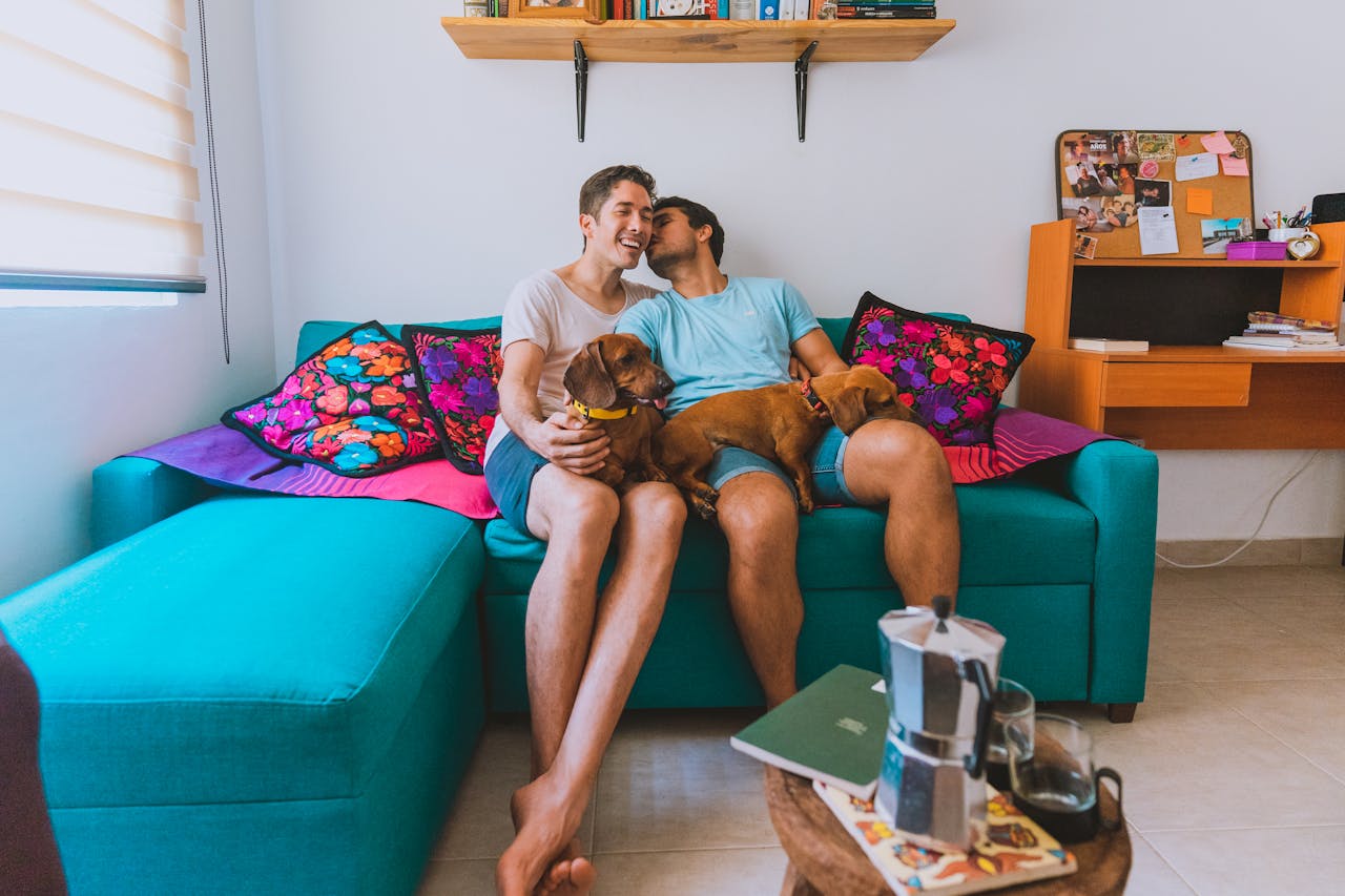 Cheerful couple enjoying time with their dachshunds on a turquoise sofa.